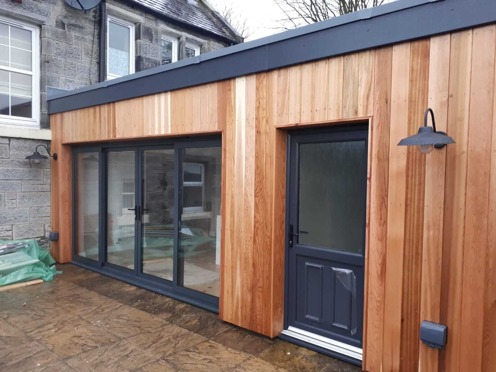 Extension to create kitchen, dining room, utility room and shower/toilet. Anthracite aluminium patio doors, cedar cladding, factre single membrane flat roof